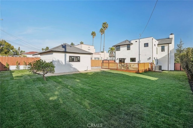 rear view of house featuring a lawn, a chimney, a fenced backyard, and a deck