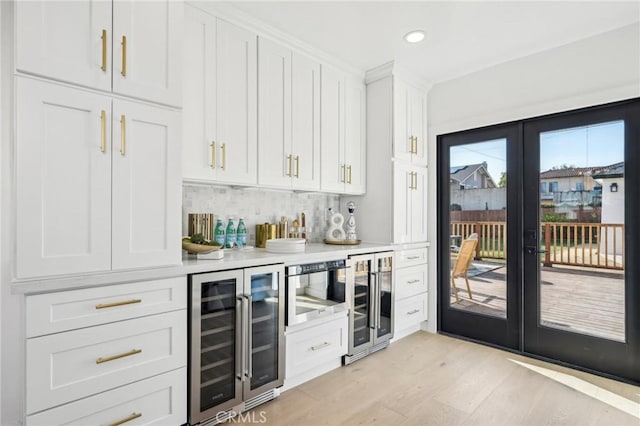 bar featuring french doors, bar area, light wood-style flooring, recessed lighting, and beverage cooler