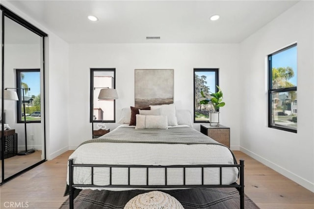bedroom with baseboards, light wood finished floors, visible vents, and recessed lighting