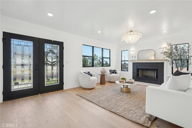 living room featuring a fireplace, wood finished floors, recessed lighting, and french doors