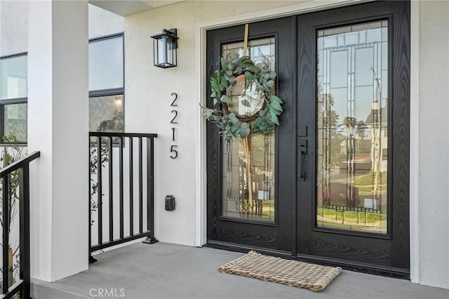 view of exterior entry featuring french doors and stucco siding