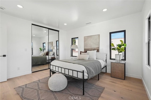 bedroom with baseboards, recessed lighting, a closet, and light wood-style flooring
