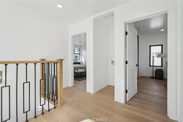 corridor featuring recessed lighting, light wood finished floors, baseboards, and an upstairs landing
