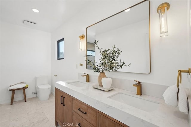full bathroom featuring toilet, a sink, double vanity, and recessed lighting