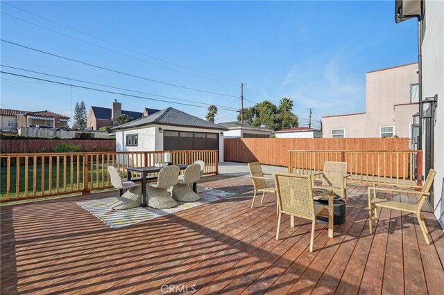 deck with outdoor dining area, an outbuilding, and a fenced backyard