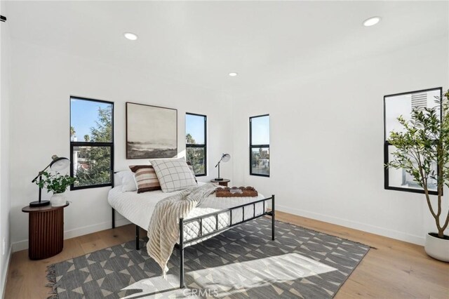 bedroom with baseboards, wood finished floors, and recessed lighting