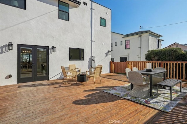 deck featuring outdoor dining area, fence, and french doors