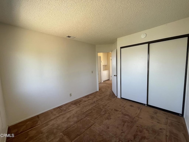 unfurnished bedroom featuring a textured ceiling, a closet, carpet, baseboards, and visible vents