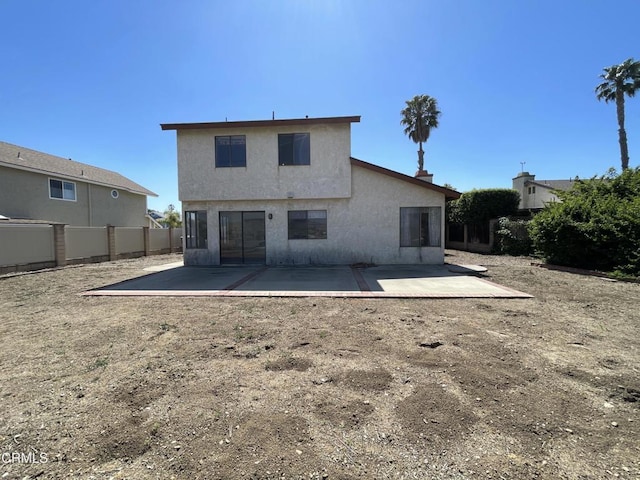 back of property with fence, stucco siding, and a patio