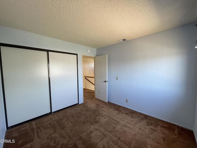 unfurnished bedroom with visible vents, carpet floors, a closet, baseboards, and a textured ceiling