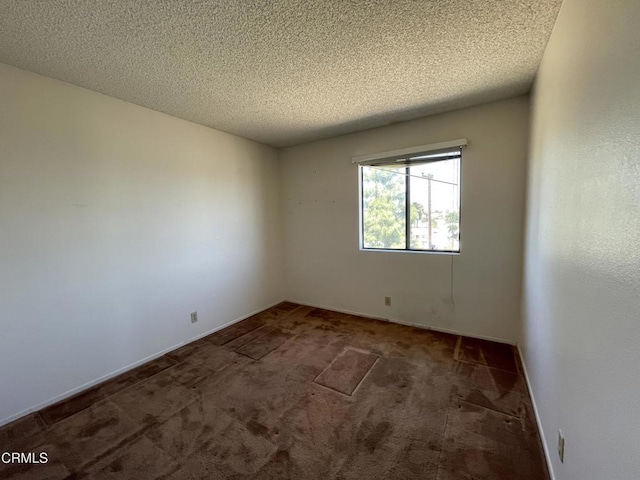 carpeted spare room featuring baseboards and a textured ceiling