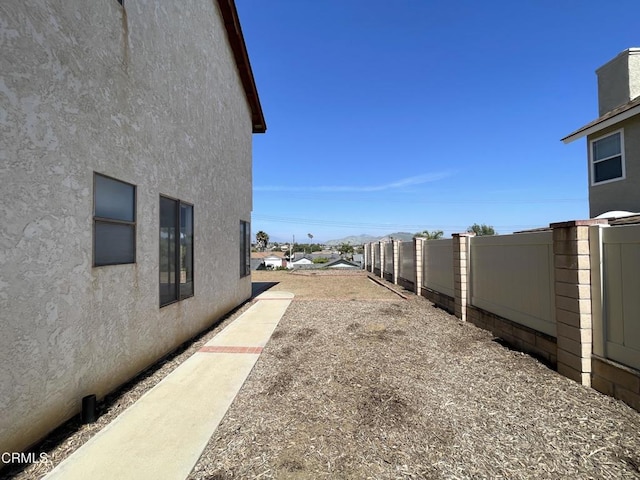 view of side of home with stucco siding and fence