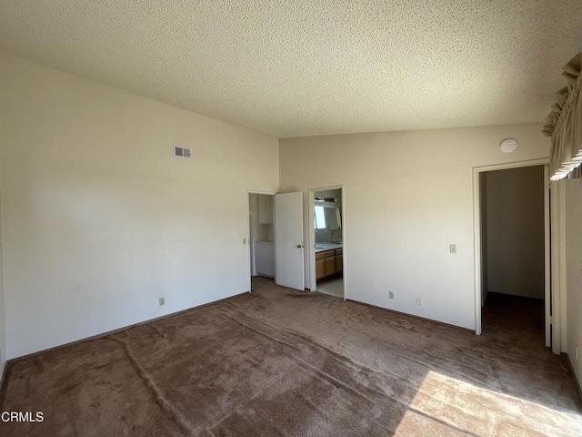unfurnished bedroom with a textured ceiling, lofted ceiling, carpet floors, and visible vents