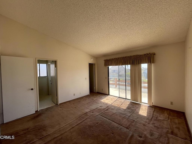 empty room featuring vaulted ceiling, a textured ceiling, and carpet flooring
