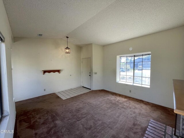 interior space featuring a textured ceiling, lofted ceiling, visible vents, and carpet flooring