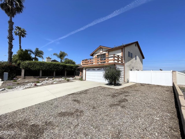 view of property exterior with fence, a balcony, stucco siding, concrete driveway, and a garage