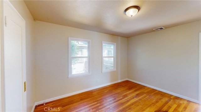 empty room featuring light wood-style floors, visible vents, and baseboards