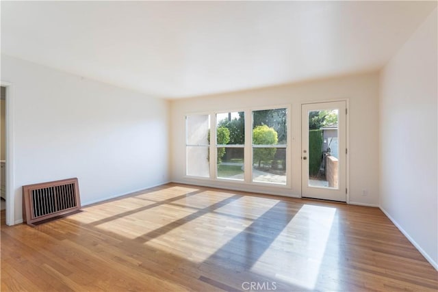 spare room with visible vents, baseboards, and wood finished floors