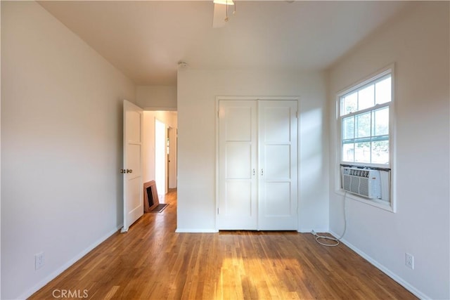 unfurnished bedroom featuring cooling unit, a closet, baseboards, and light wood-type flooring