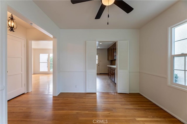 unfurnished room with light wood-type flooring, a wealth of natural light, and ceiling fan