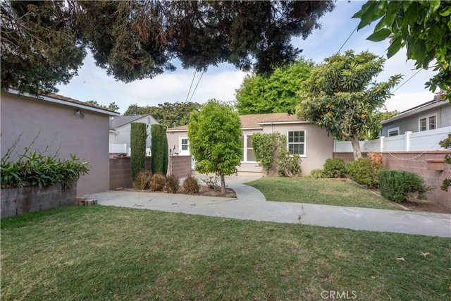 view of front of home featuring stucco siding, fence, and a front yard