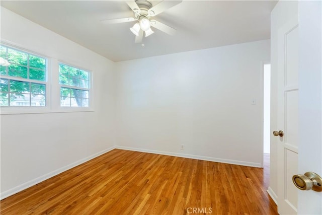 spare room featuring light wood-type flooring, a ceiling fan, and baseboards