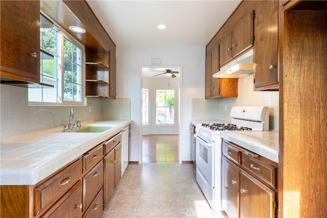 kitchen featuring a sink, a ceiling fan, white appliances, under cabinet range hood, and tile countertops