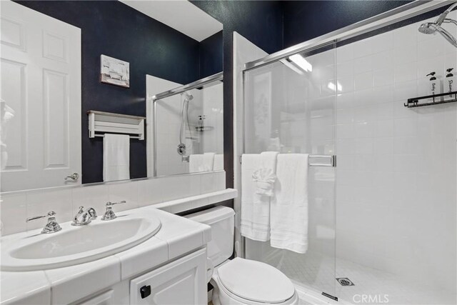 full bathroom featuring toilet, vanity, and a stall shower