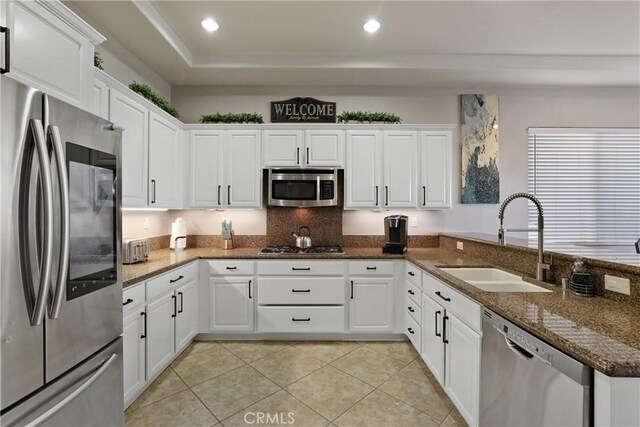 kitchen featuring stainless steel appliances, a sink, white cabinetry, and light tile patterned flooring