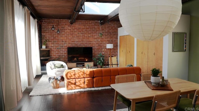 living room featuring wood finished floors, beam ceiling, and brick wall