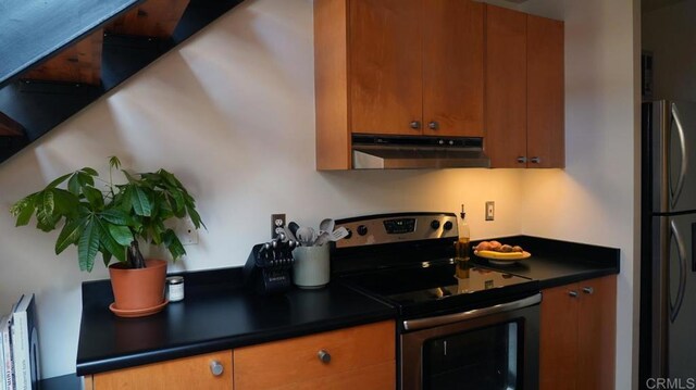 kitchen featuring brown cabinets, freestanding refrigerator, electric stove, and under cabinet range hood