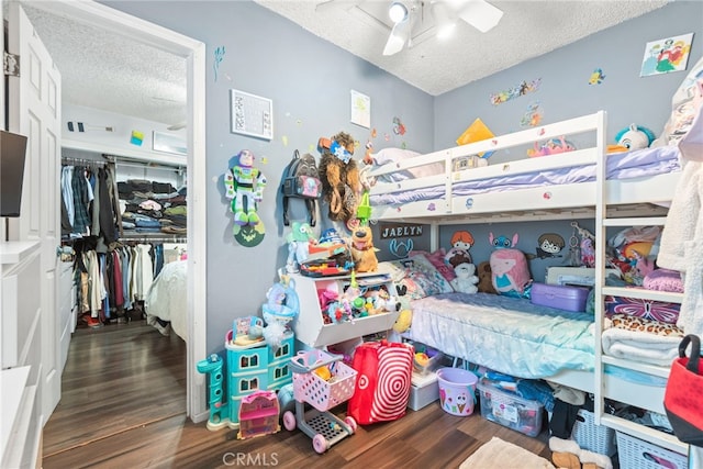 bedroom featuring a textured ceiling, ceiling fan, wood finished floors, and a closet