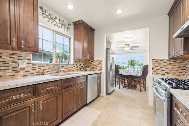 kitchen with stainless steel appliances, a ceiling fan, decorative backsplash, and a sink