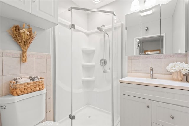 bathroom featuring vanity, a shower stall, toilet, and tile walls