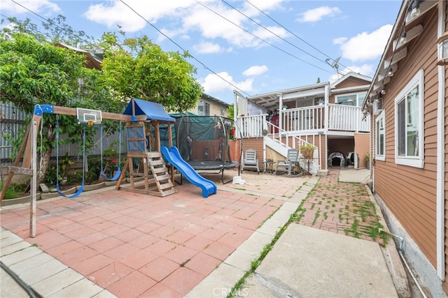 view of play area with fence, a trampoline, a patio area, and stairway