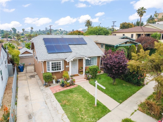 bungalow-style house with roof with shingles, a residential view, solar panels, and a front yard
