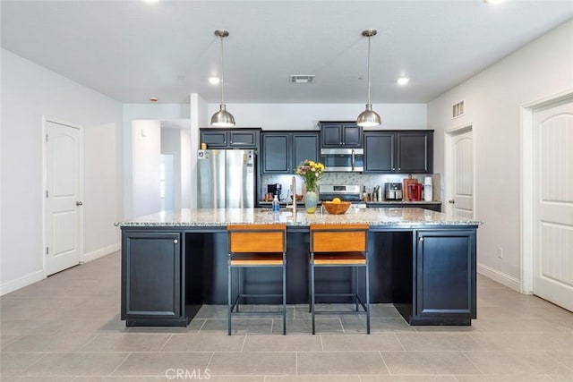 1628 N Delbert Ave, Fresno, CA 93722 - kitchen with visible vents, light stone counters, appliances with stainless steel finishes, and a spacious island