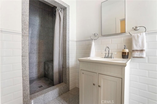 full bath featuring vanity, a stall shower, and tile walls
