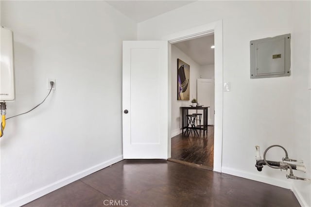 interior space featuring water heater, electric panel, baseboards, and wood finished floors