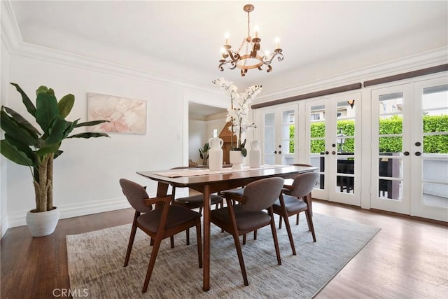 dining area featuring french doors, light wood-type flooring, crown molding, baseboards, and a notable chandelier
