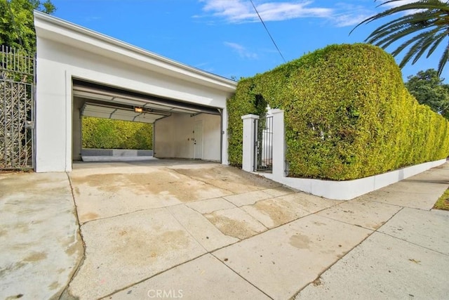 garage featuring a gate, driveway, and fence
