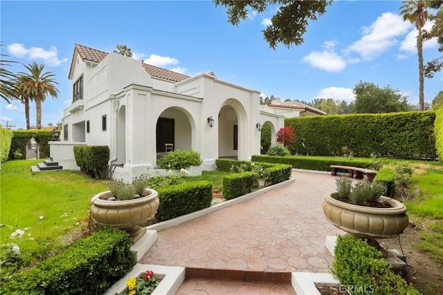exterior space featuring stucco siding, a tile roof, and a front yard