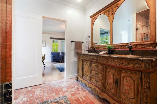 bathroom with a sink, a shower, double vanity, baseboards, and ornamental molding