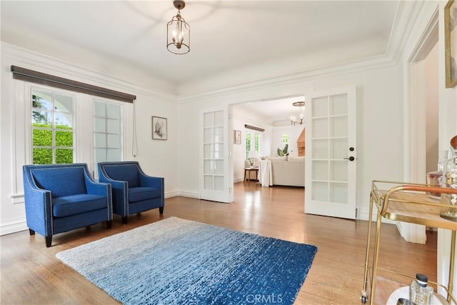 living area with baseboards, french doors, wood finished floors, and an inviting chandelier