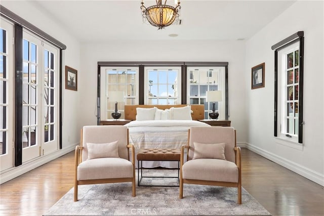 bedroom featuring baseboards, a chandelier, and wood finished floors