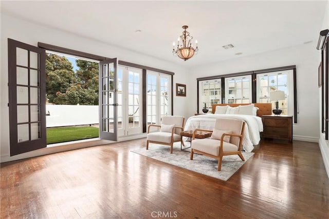 bedroom with baseboards, a notable chandelier, wood finished floors, and access to exterior