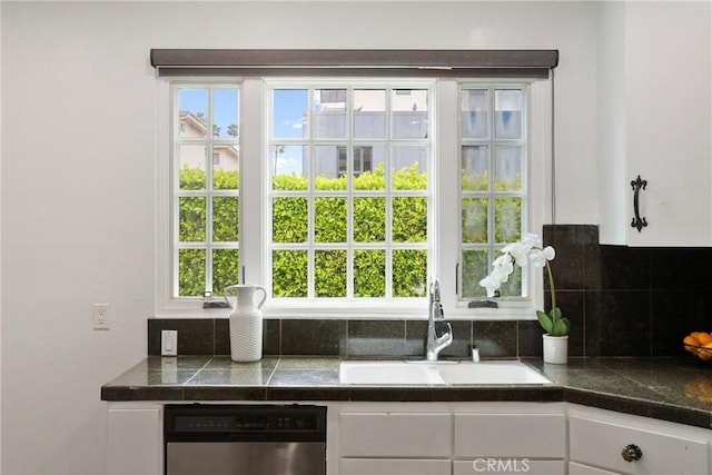 interior space featuring tile counters, a sink, dishwasher, and white cabinetry