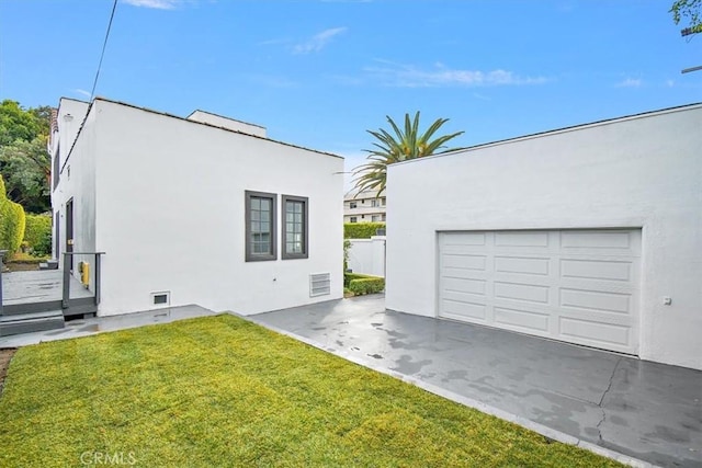 view of side of home with stucco siding, fence, and a yard