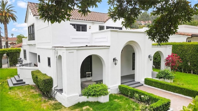back of house featuring a porch, a tiled roof, and stucco siding