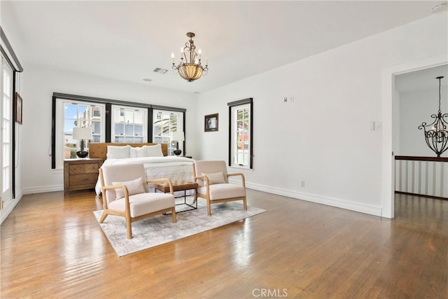 bedroom featuring visible vents, baseboards, wood finished floors, and a notable chandelier